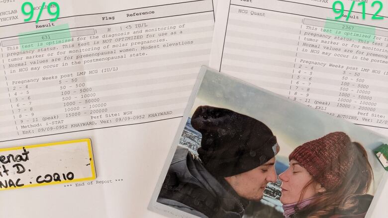 A photograph of a couple embracing lays atop health reports about a pregnancy. In the photo, the couple are outdoors in winter coats and hats, and are leaning in to kiss with eyes closed.