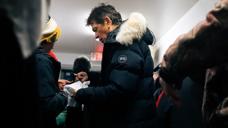 Ted Nolan signs a kid's jersey with a sharpie. 