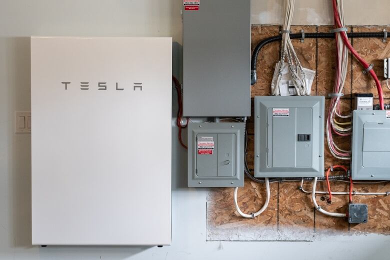 A battery panel and two electrical panels installed on the interior wall of a building.