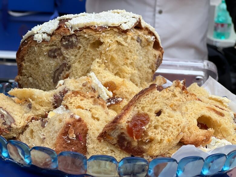 Panettone sweet bread slices containing apricot and white icing on a blue glass platter.