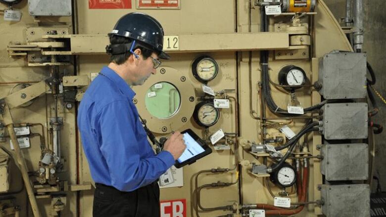 A man wearing a hard hat using a tablet