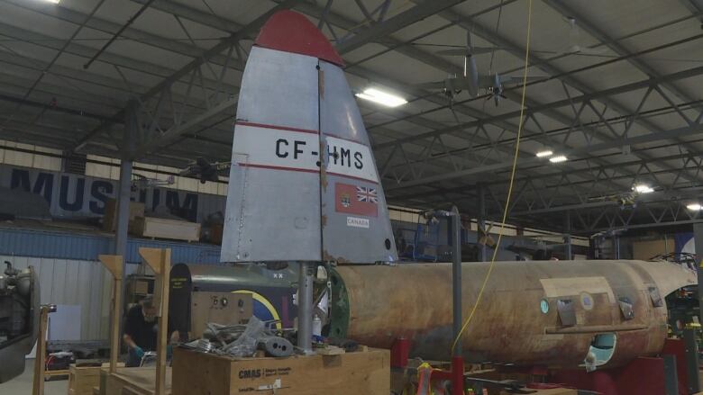 An airplane with a grey tail sits in a warehouse.