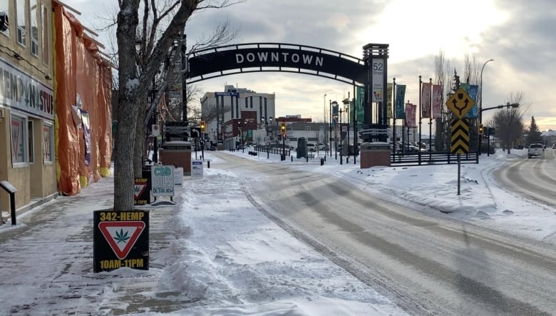 A snow covered road leads under a sign that welcomes visitors to downtown Red Deer.