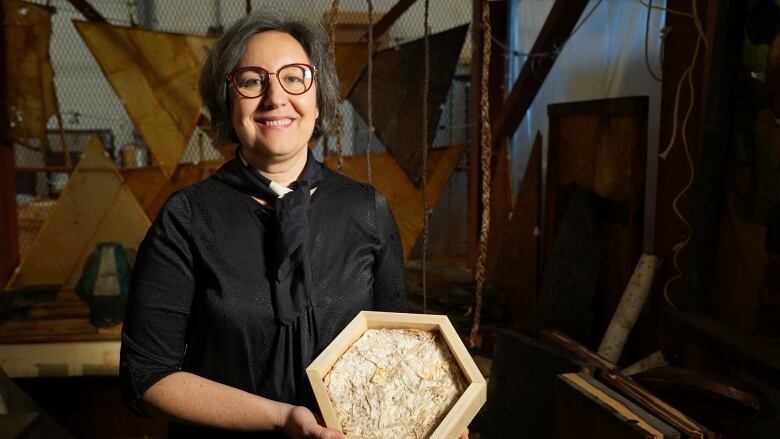 Mercedes Garcia-Holguera holds a hexagonal brick that looks like cement mixed with straw.