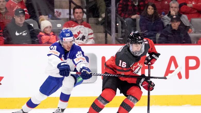 Connor Bedard skates the puck away from another player