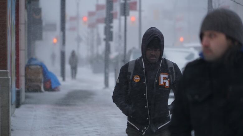 People walk through blizzard conditions on Dundas Place in London, Ont.