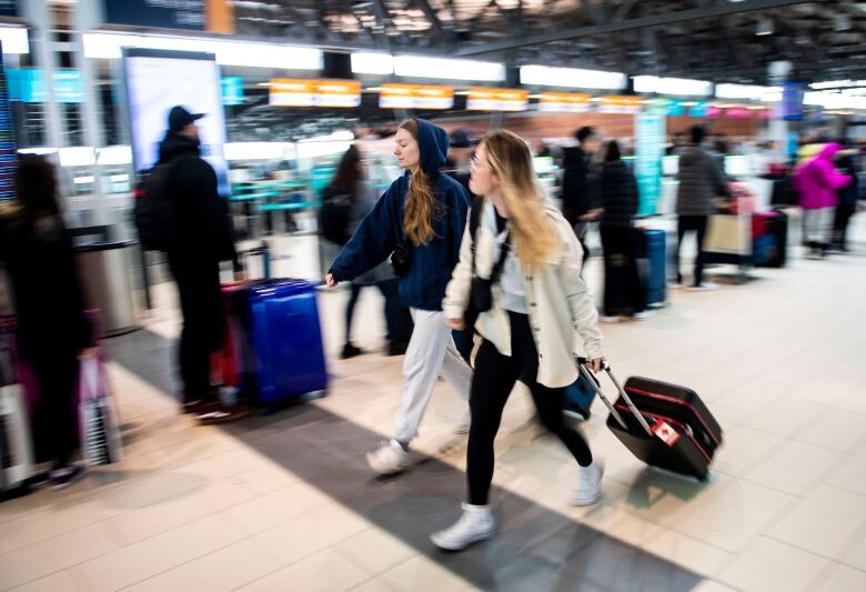 Travellers walking through an airport.