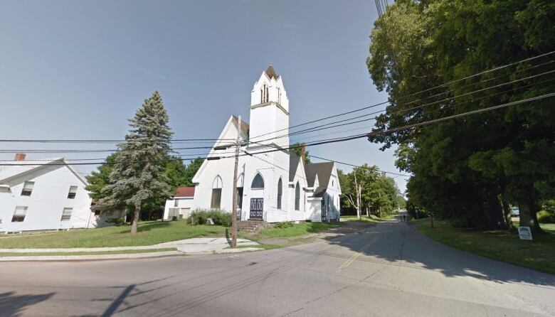 A white church stands on the corner of an intersection, as Chapel Road stretches into the distance.