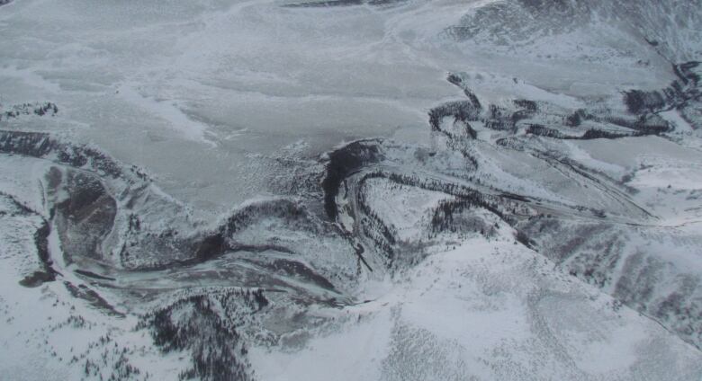 An aerial photo of a river windy it's way through a snowy landscape.