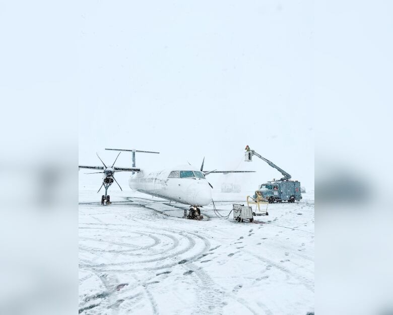 An aircraft taxis on an airport runway covered with snow.