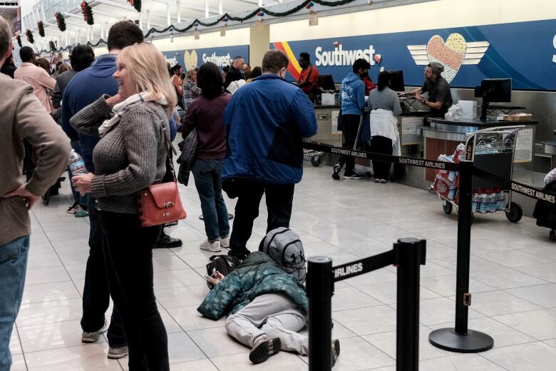 A traveller lies on the floor in the line for a Southwest counter. 