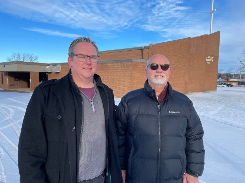 Two people stand in front of the Calvary Church in Charlottetown.