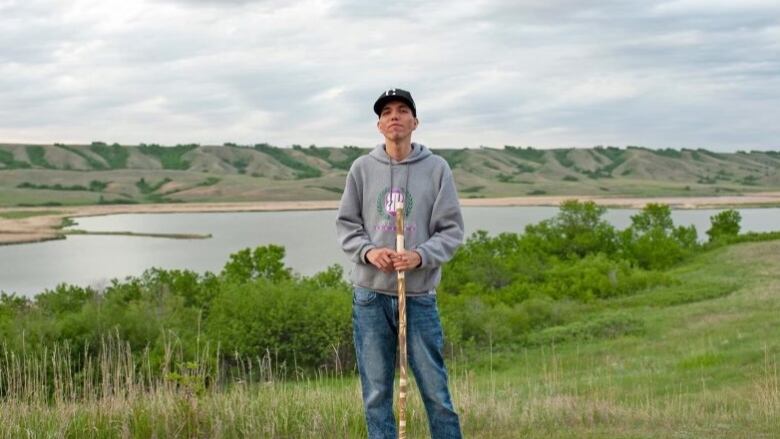 Cole Cappo standing in front of a body of water in his home community of Muscowpetung Saulteaux Nation.