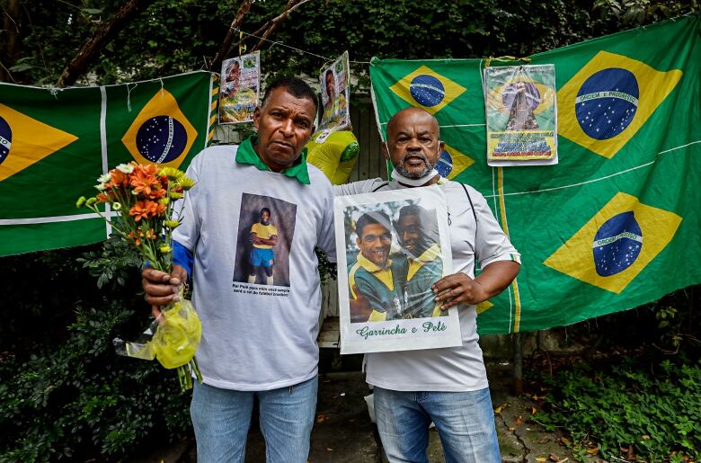 Two men hold memorabilia honoring Pele.