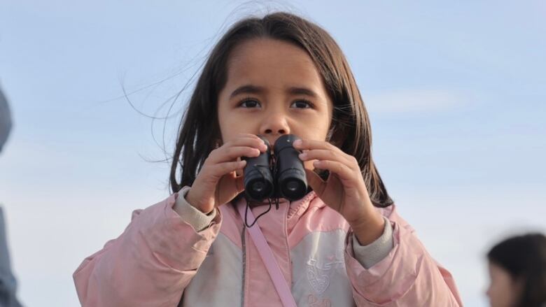 A small child holds binoculars