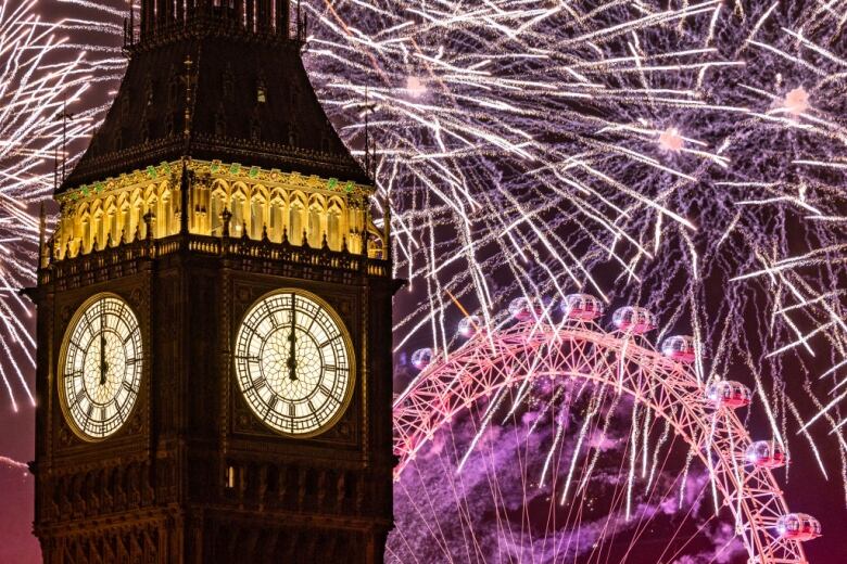 Fireworks light up the night sky around the London Eye and Big Ben as its hands show midnight.