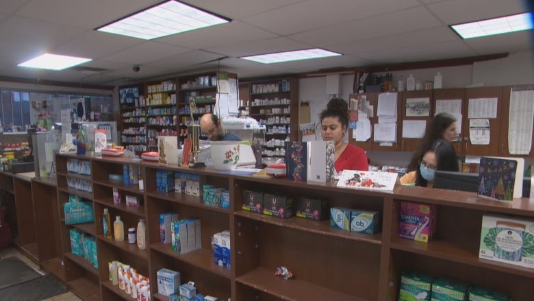 three people working behind the counter at a pharmacy