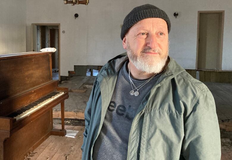 A man with a beard and a toque stands inside a former church that is being renovated.