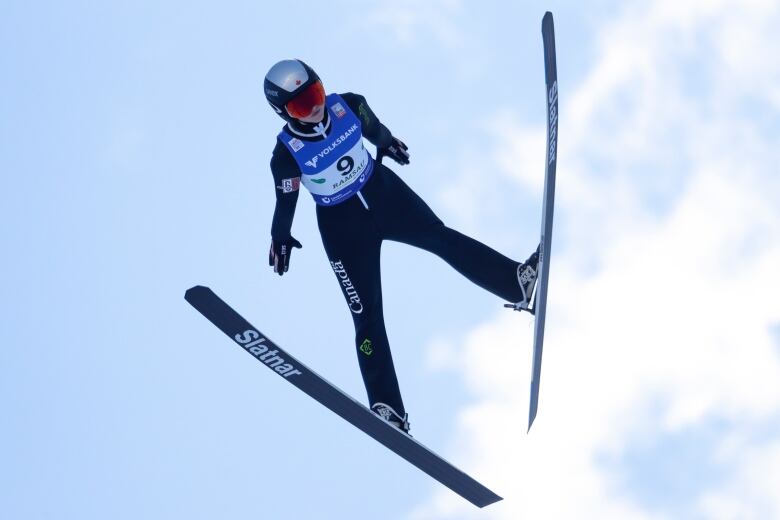 A female ski jumper soars through the air.