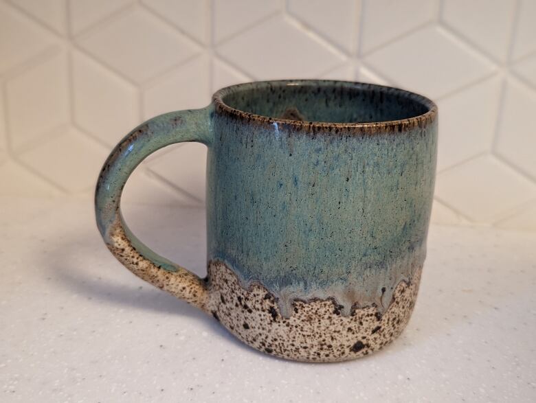 A green coffee mug on a countertop.