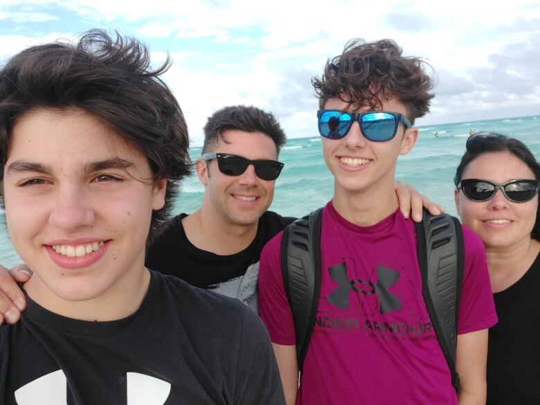 Selfie of family of four on a beach. 