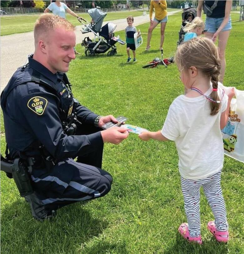 A uniformed OPP officer talking to a little girl.