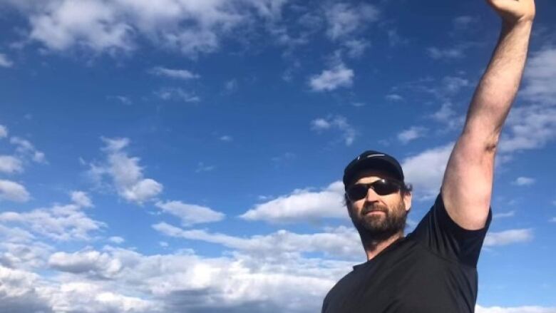 A man poses in front of a mountainscape. 