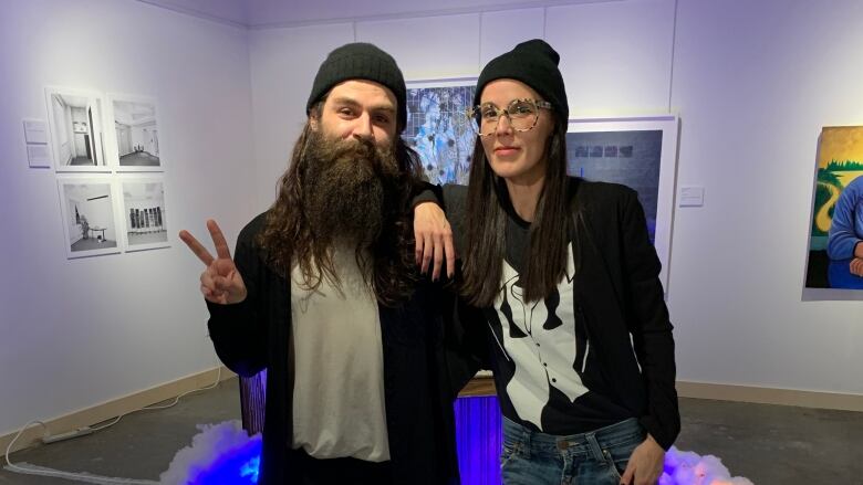 Sarah Swan (right), director with the Yellowknife Artist Run Community Centre - or YK ARCC - poses with artist Sami Blanco in front of his installation at the city's visitor centre gallery. 