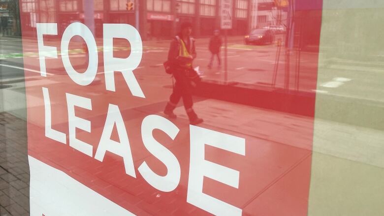 For lease sign in window and reflection shows person walking on sidewalk