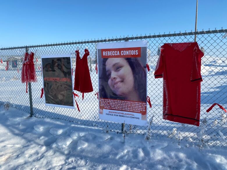 Signs and red dresses hang on a fence outside a landfill south of Winnipeg.