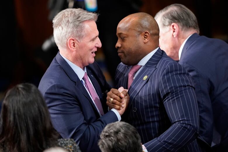 Two men grasp hands in greeting each other.