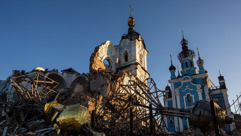 The lighting on the debris suggests the sun is low in the sky. A blue building farther away from the camera appears to be intact.