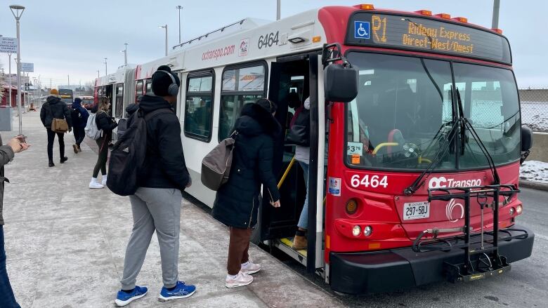 People board a red-and-white bus with R1 on the front screen.