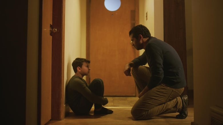 A still shot from the film He Would Say shows a father crouching down, speaking to his young son. 