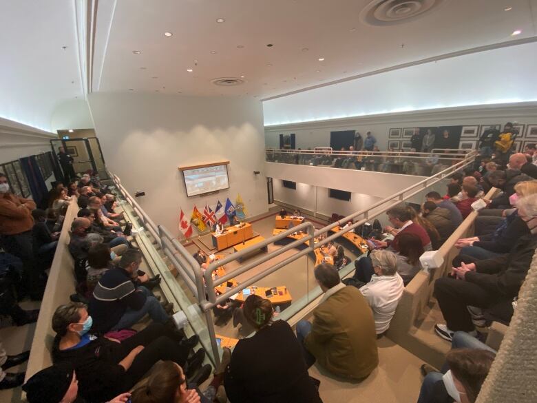 People sit in the upstairs gallery of a city hall council chamber.