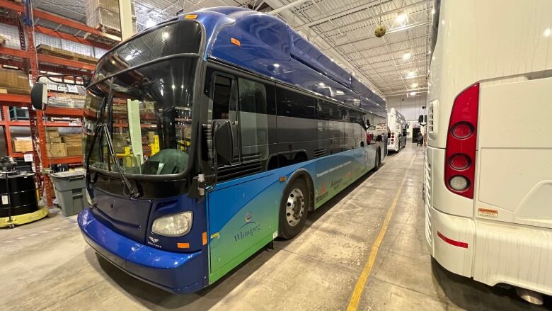 A blue New Flyer transit bus is seen in a garage.