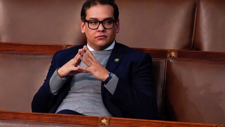 Man with dark hair and glasses sits alone in the U.S. House of Representative.