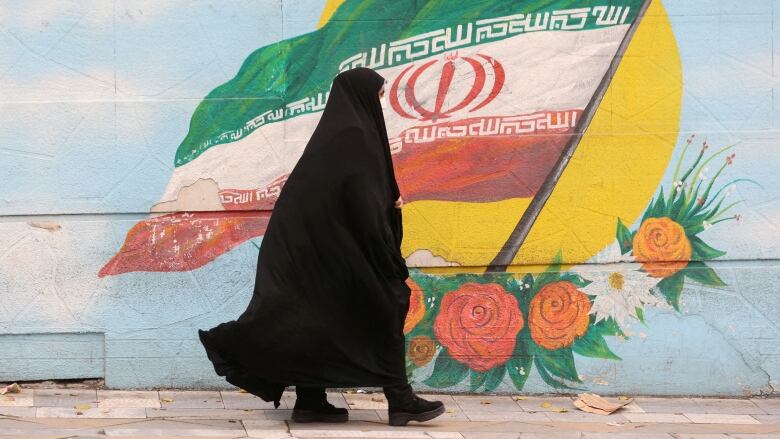 A woman walks on a street in Tehran.