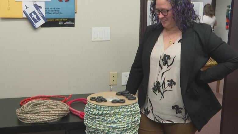 Melanie Giffin, a marine biologist with the PEIFA shows different break-free fishing gear options on a table. The gear includes four colorful ropes and small round black clasps. 