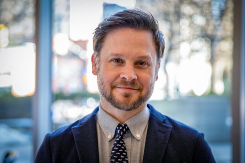 Brett Gilchrist, the Department of Fisheries and Oceans director of national programs stands for a headshot photo in a blue suit and tie.