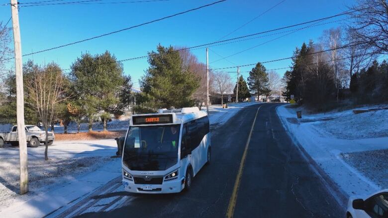 An aerial shot of a small bus driving down a two lane road. 