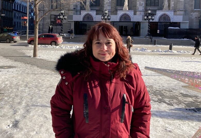 A woman in a burgundy jacket stands in front of Notre Dame Cathedral in Old Montreal.