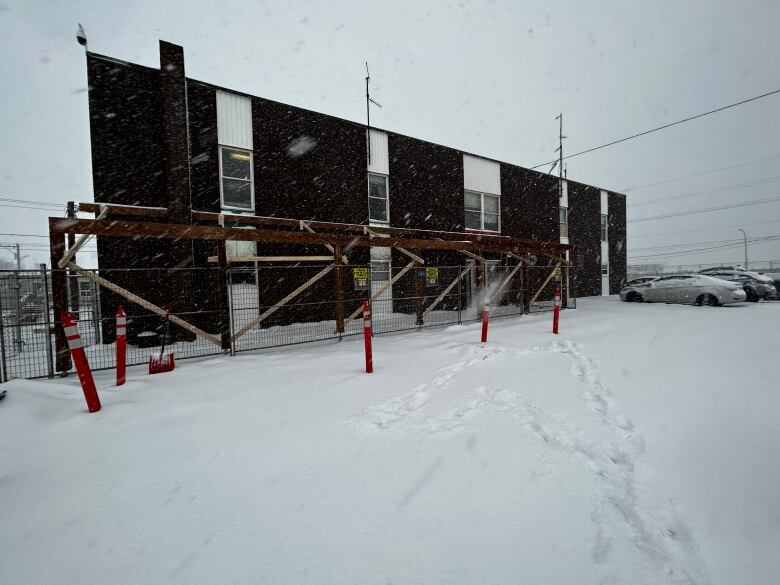 A two-storey building with construction materials outside, in a snowy landscape.