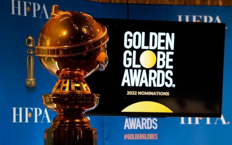 A golden statue of a globe is pictured, with a television screen that reads GOLDEN GLOBE AWARDS just behind it.