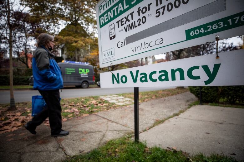 A person walks past a 'no vacancy' sign.