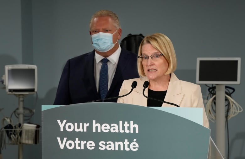 A politician makes an announcement while a province's premier stands behind her.