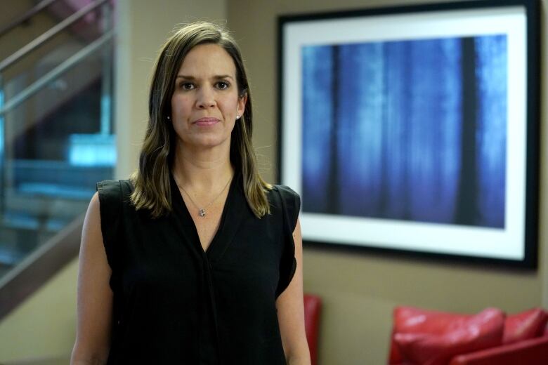 A woman in a dark shirt stand in a lobby, facing the camera