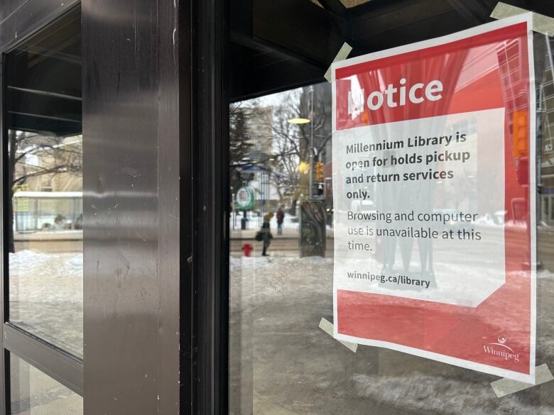 A sign posted to a window at the Millennium Library reads: 'the Millennium Library is open for holds, pickup and return services only.'