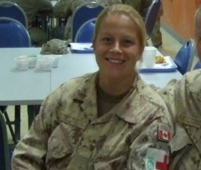 A woman wearing a camouflage sitting at a table.