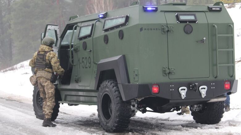 A Ukrainian soldier standing beside a military vehicle.